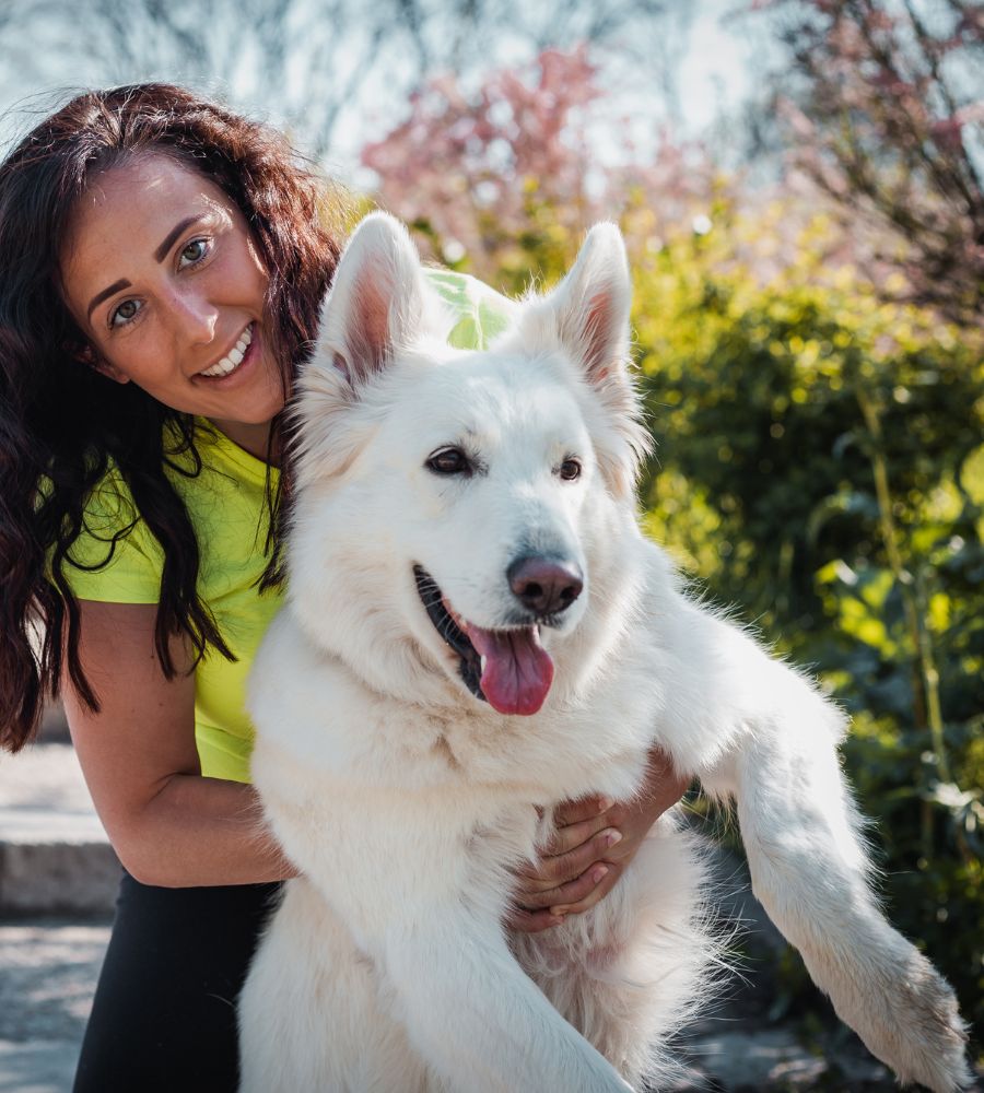 a person in a yellow shirt holding a white dog